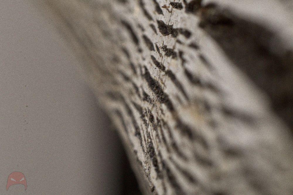 A side shot of a chipboard table slowly coming apart. The foreground and background are blurred, while the midground is in focus