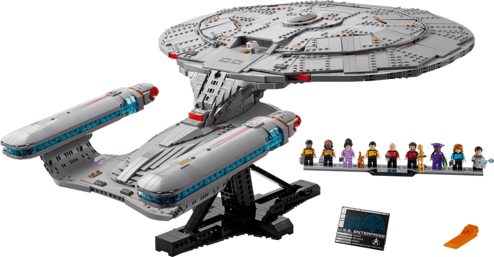 A lego version of the Enterprise D from the show Star Trek: The Next Generation. To the right of the ship is a line up of character minifigs